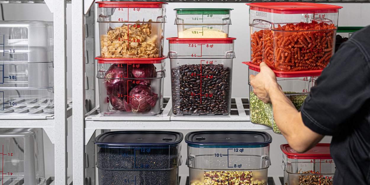 A variety of stackable, clear polycarbonate food storage containers with color-coded lids.