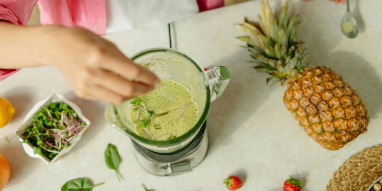 Blending green smoothie with fresh fruit in blender for food processing