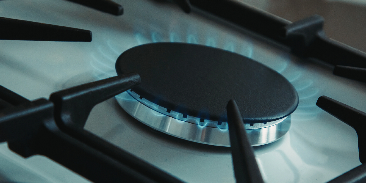 A close-up of a high-efficiency commercial gas range burner ignited with a precise blue flame, featuring heavy-duty cast iron grates.
