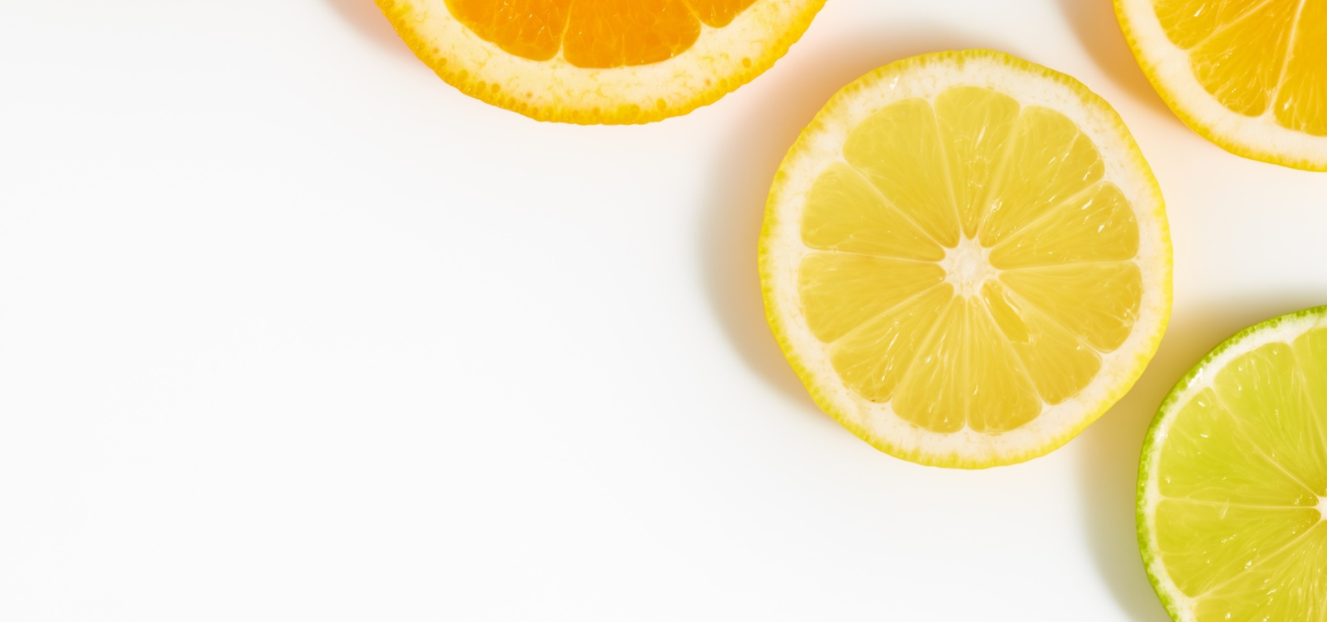 Sliced fresh lemons scattered on a clean white background.