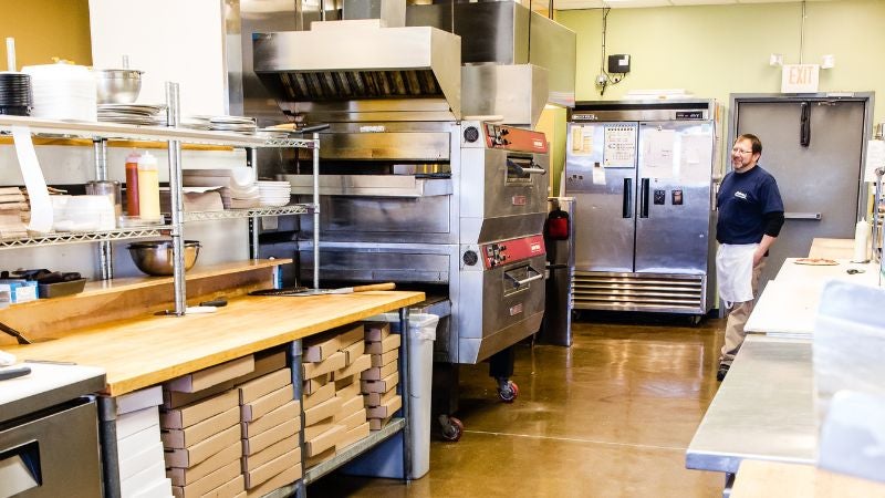Arturo’s Pizza Kitchen with commercial equipment. Chef in the back.