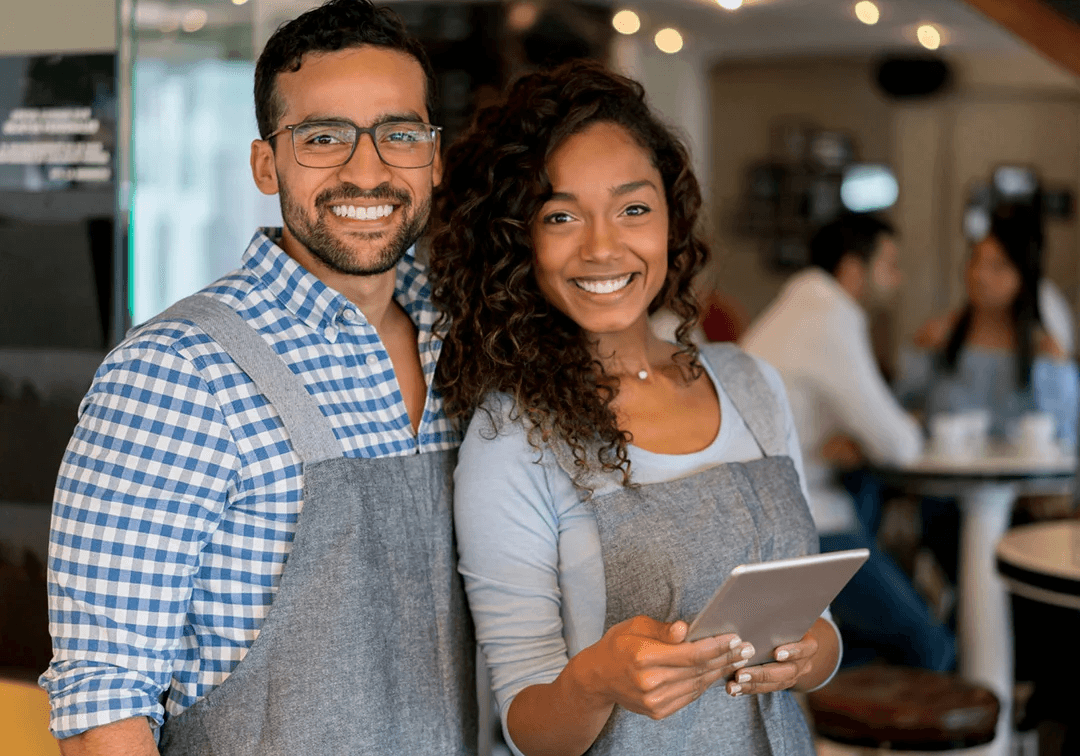 Two people standing together in a casual setting, one holding a tablet.