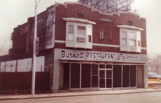 Abandoned building with 'Burkhett Restaurant Equipment' sign on a street corner.