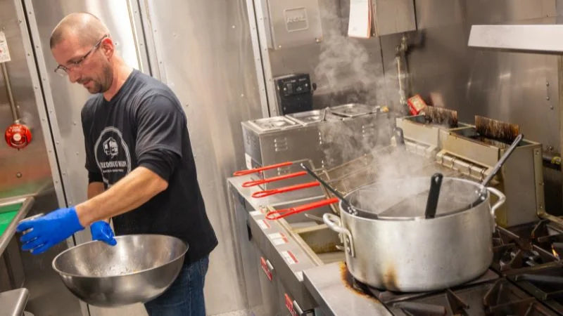 Person working in a kitchen with pots and pans on a stove