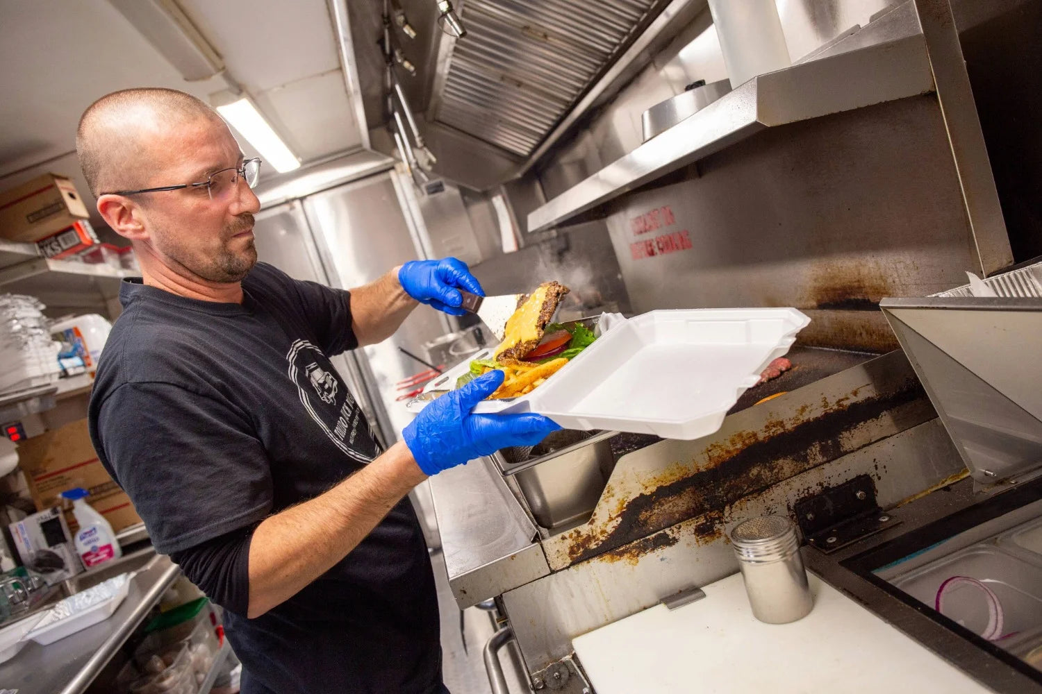 Chuck Wagon food truck owner preparing burger and fries with blue gloves