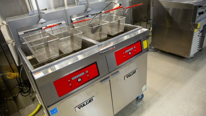 Commercial deep fryers with baskets in school cafeteria kitchen for high-volume food preparation