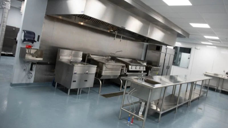 Commercial kitchen with cookline, prep table, and stainless steel workstations in municipal facility