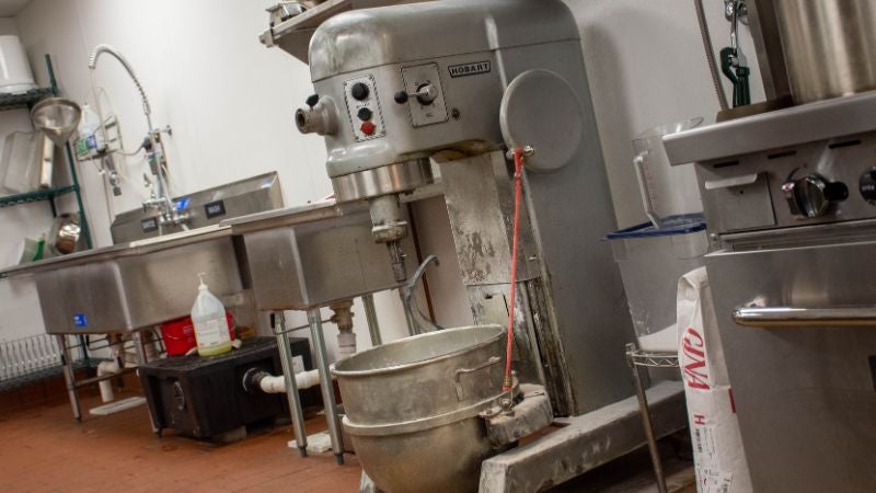 Commercial Hobart floor mixer in dish/prep area with three-compartment sink in background