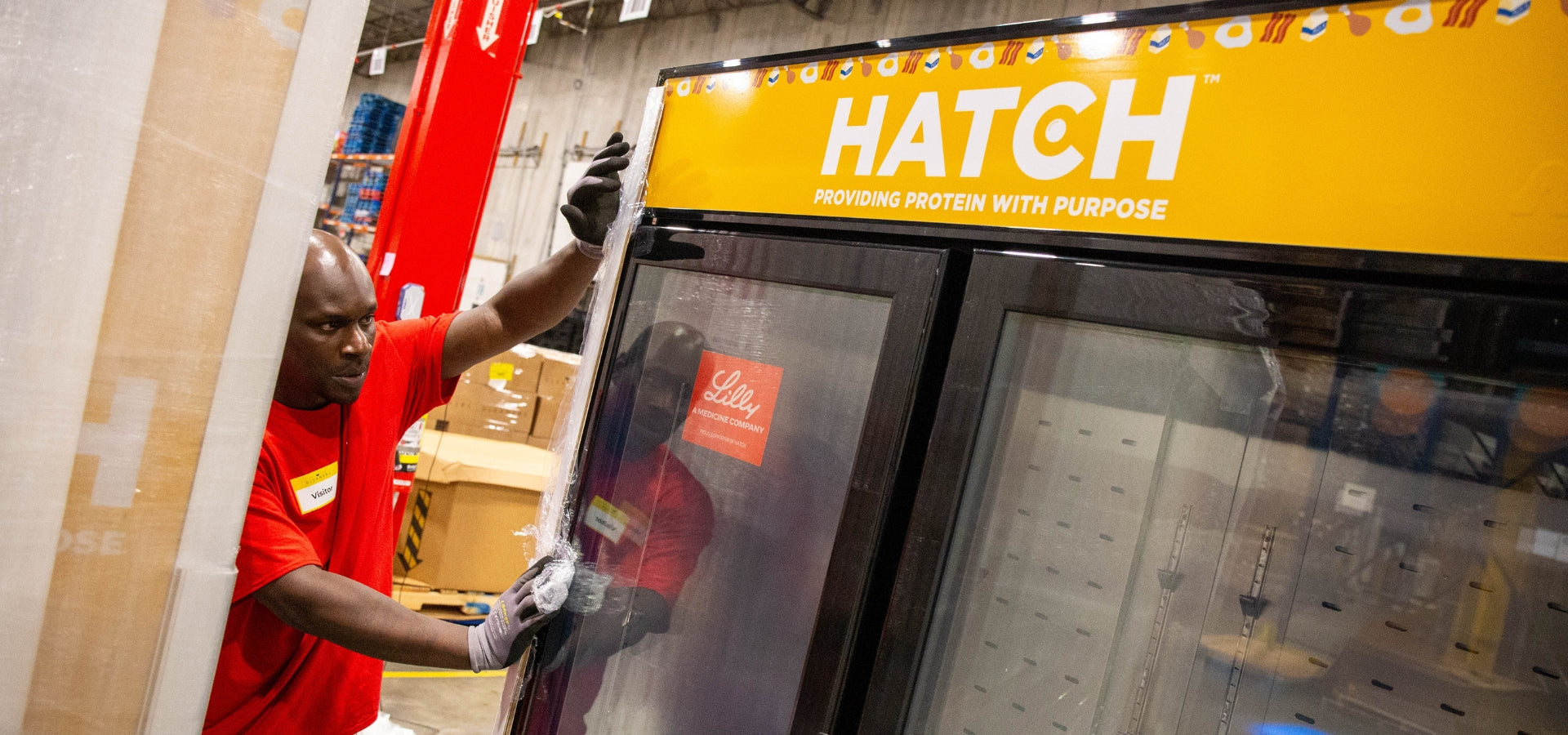 Burkett Restaurant Equipment worker unloading a custom-branded HATCH for Hunger refrigerated merchandiser