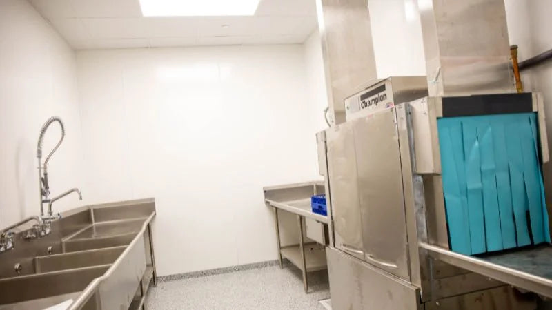 Commercial dishwashing area with conveyor dishwasher and three-compartment sink