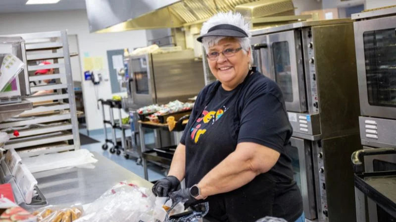 Person working in a kitchen with stainless steel appliances and baking equipment.