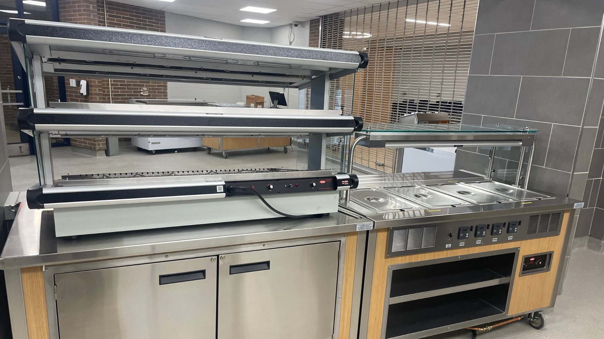 Commercial kitchen equipment including a large stainless steel counter with shelves and an oven.