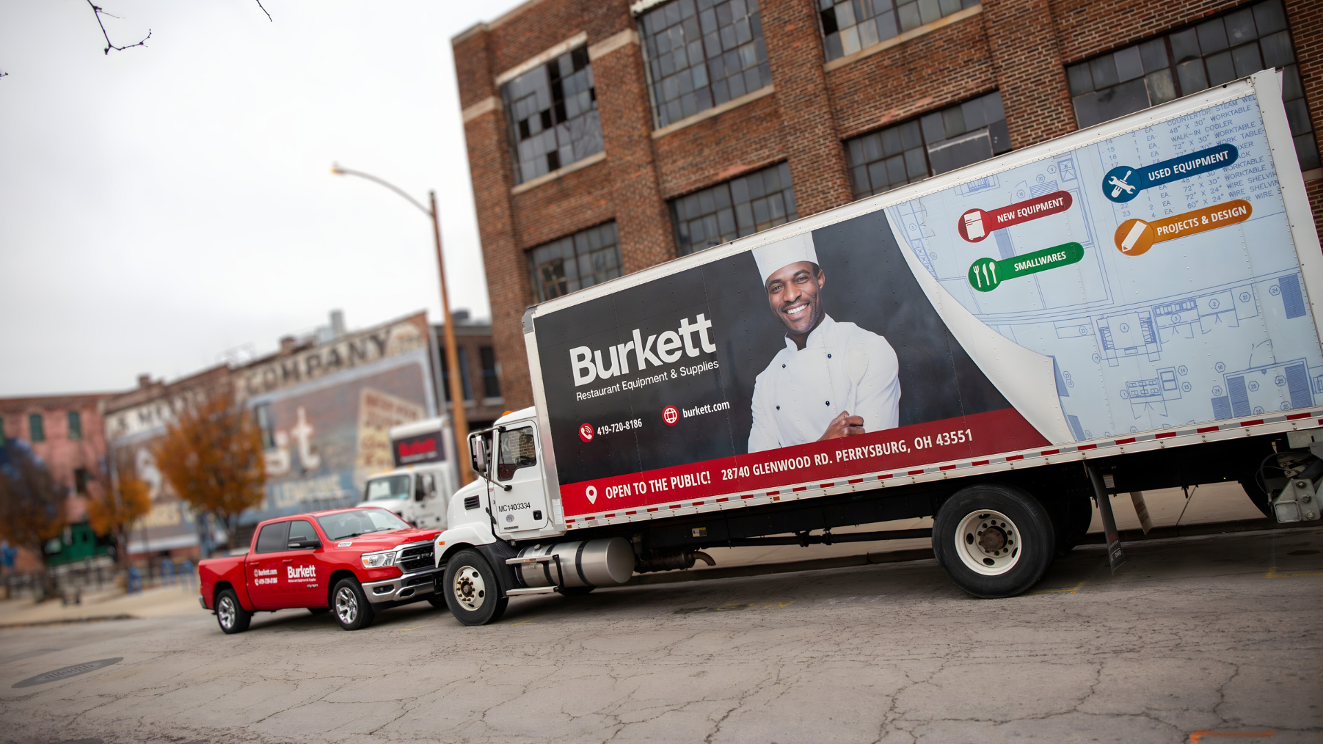 Burkett truck with a large advertisement on a city street.