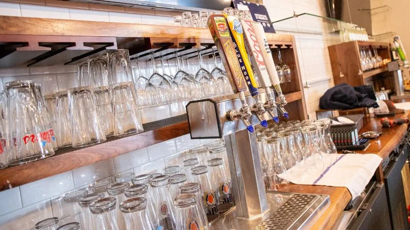 Bar beer tap system with multiple draft handles and glassware storage on shelving