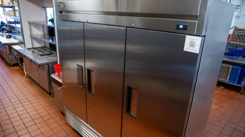 Stainless steel refrigerator in a kitchen setting with tiled floor