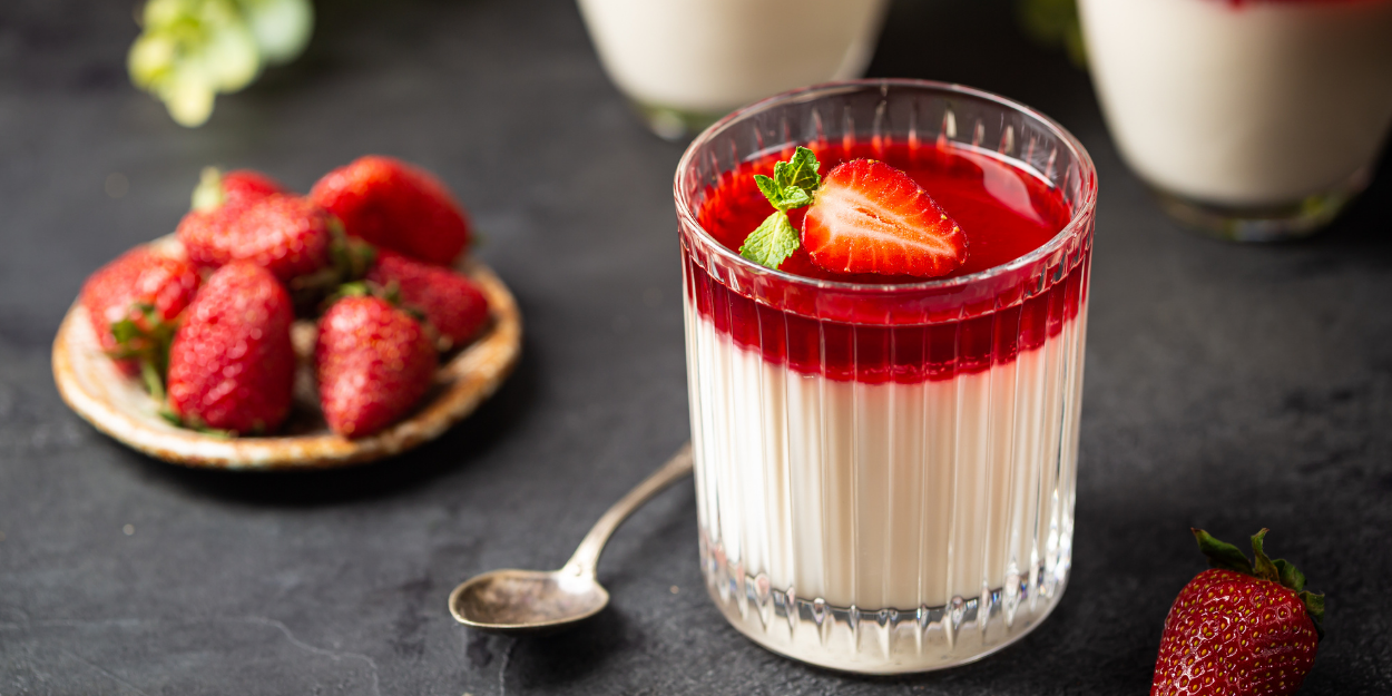 A vibrant layered dessert featuring fresh strawberries and cream in a glass.