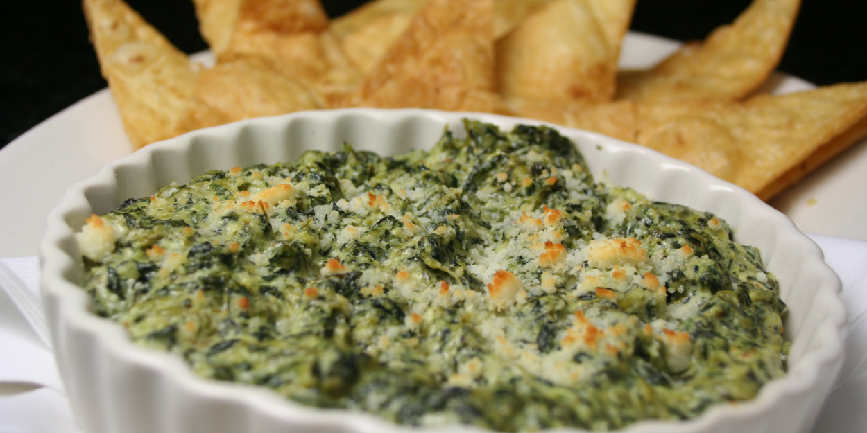Creamy spinach dip with cheese served in a bowl made in a broiler with crispy tortilla chips