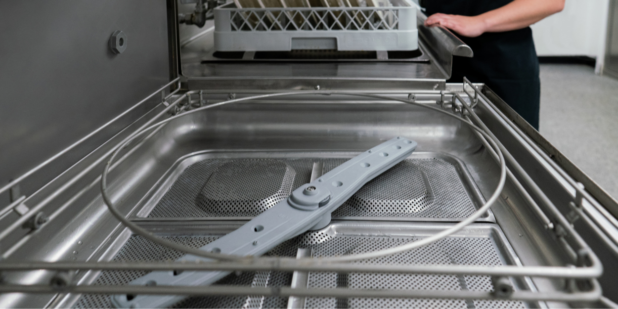 Commercial dishwashing machine interior featuring stainless steel tank, filter system, and wash arm, engineered for high-volume restaurant sanitation.