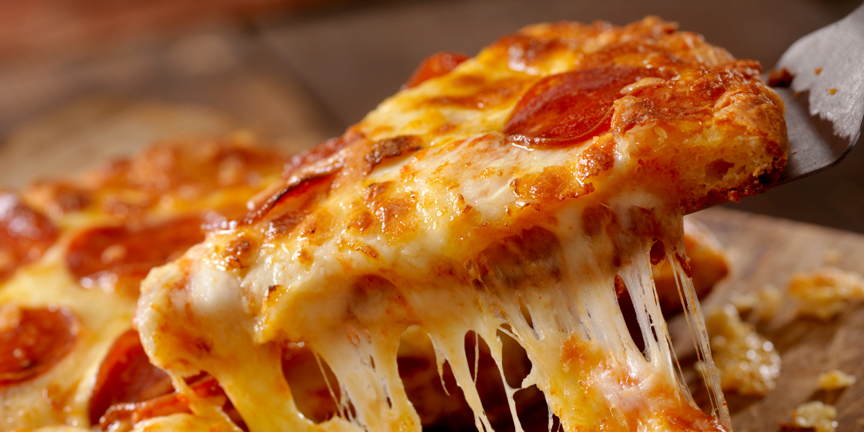 Close-up of a pepperoni pizza slice with melted cheese being served, representing professional pizzeria equipment and commercial baking supplies."