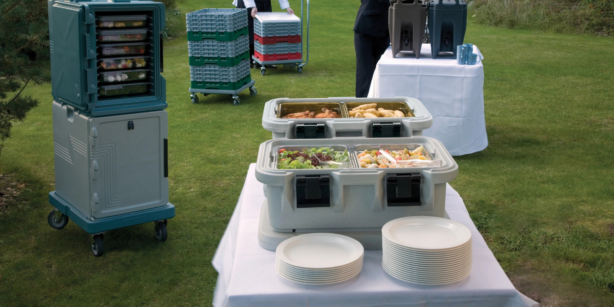 Professional catering setup featuring insulated food pan carriers, stackable transport containers, and heavy-duty utility dollies for efficient off-site food storage and transport.