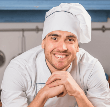 Chef wearing a white uniform and hat in a kitchen setting