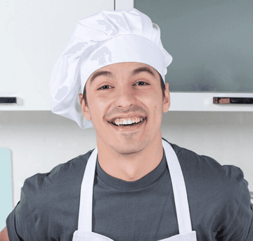 Man wearing a chef's hat and apron in a kitchen setting