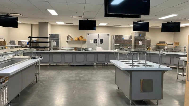Commercial cafeteria serving line with stainless steel food stations and sneeze guards