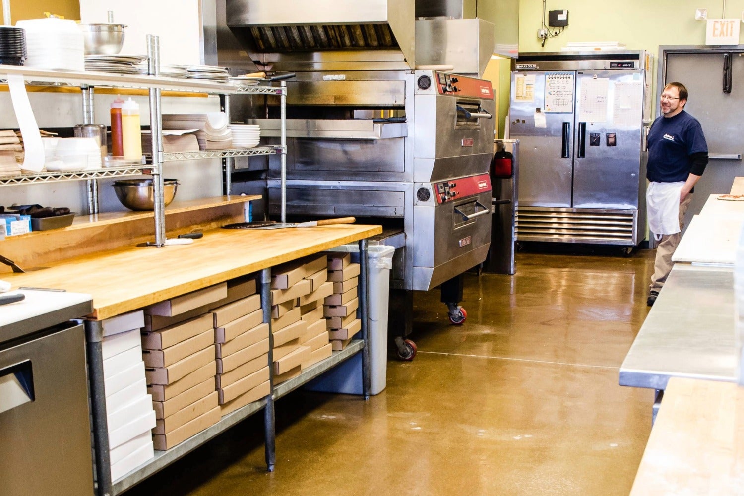 Arturo’s kitchen commercial pizza prep area with deck oven and stacked pizza boxes