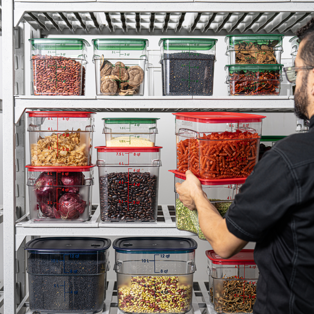 Person organizing Cambro food storage containers in a pantry