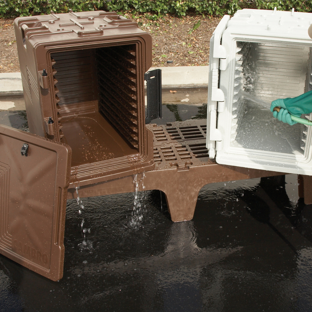 Two Cambro insulated food carriers being sprayed down with water