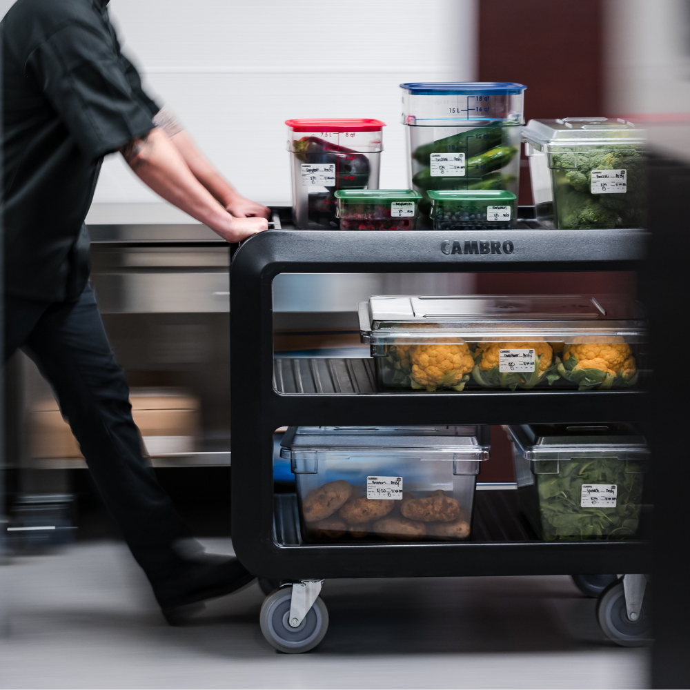 Person pushing a Cambro cart carrying Cambro food pans and storage containers