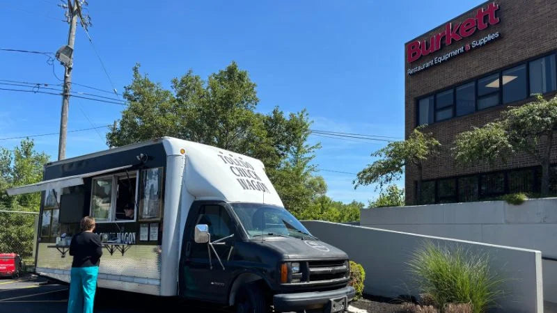 Food truck parked in front of a building with 'Burkett' branding