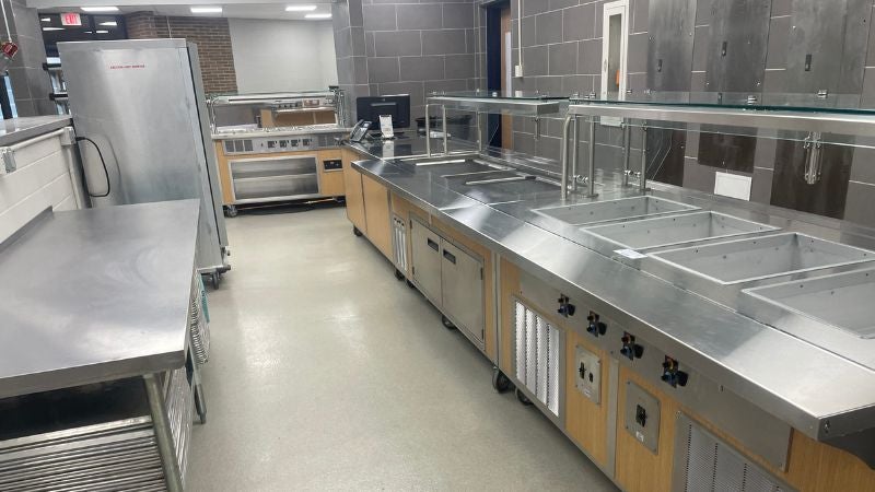 School cafeteria serving line with stainless steel counters and food wells for meal service