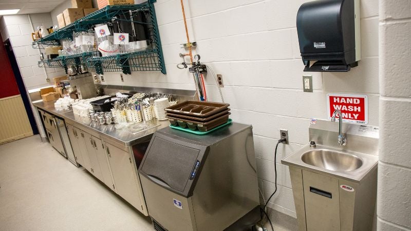 School cafeteria prep area with ice machine, storage shelving, and handwashing sink