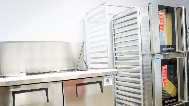 Coffee shop prep area with convection ovens, storage racks, and stainless steel counter