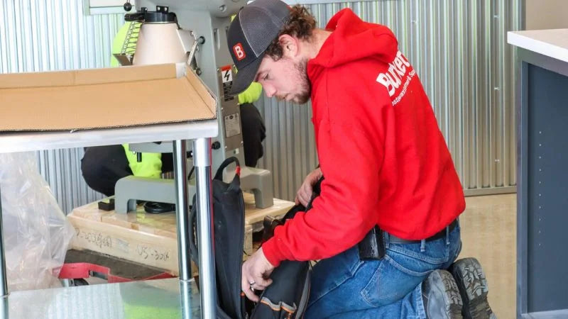 Technician installing equipment under coffee shop service counter during buildout