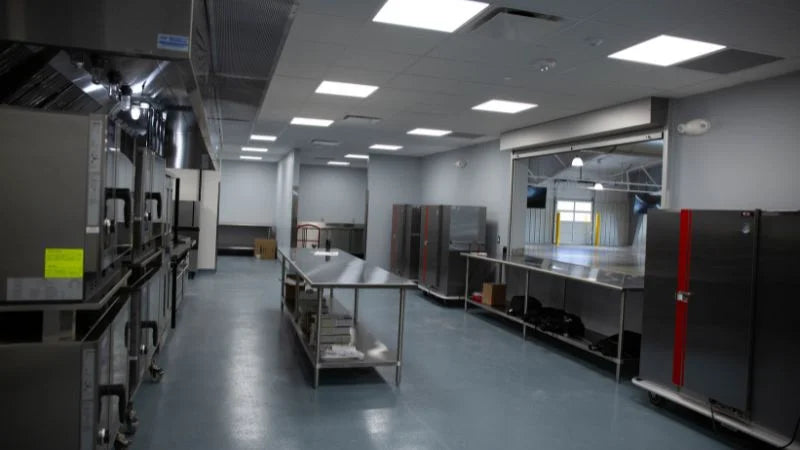 Commercial kitchen cookline with fryers, tilting skillet, and range under ventilation hood