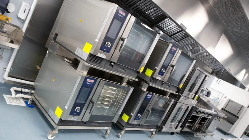 Stacked commercial convection ovens and cooking equipment in institutional kitchen