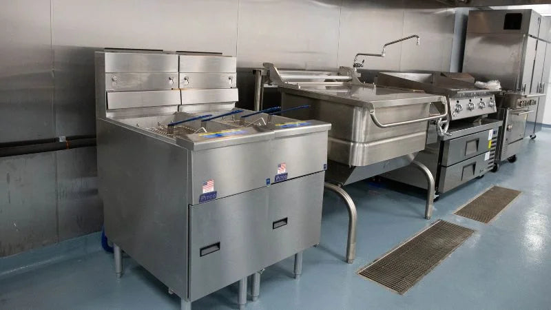 Commercial kitchen fryers and tilting skillet in high-volume food production area