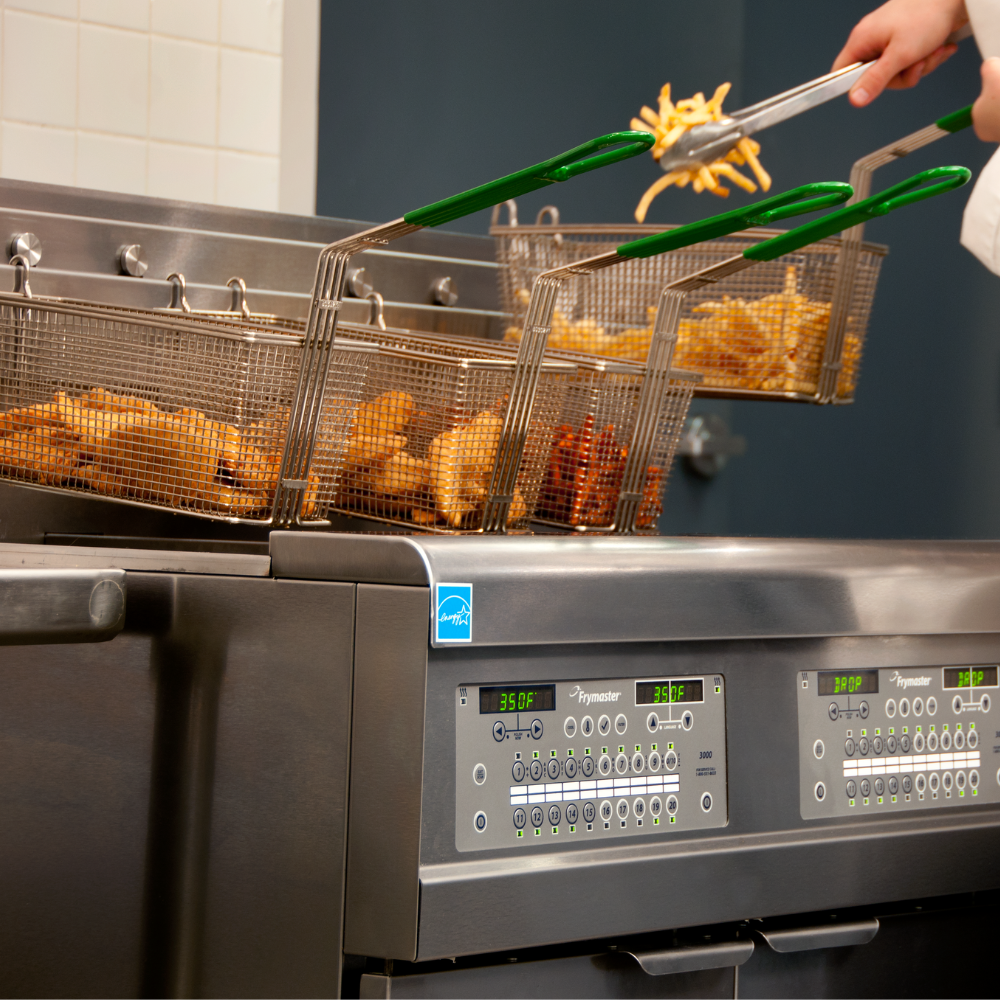 Commercial deep fryer with food being lifted out using tongs
