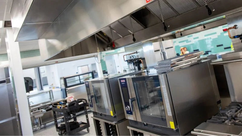 Large stainless steel exhaust hood over commercial cooking line