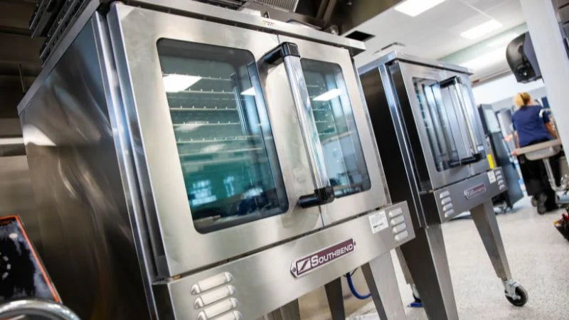 Stainless steel convection ovens on casters in commercial kitchen