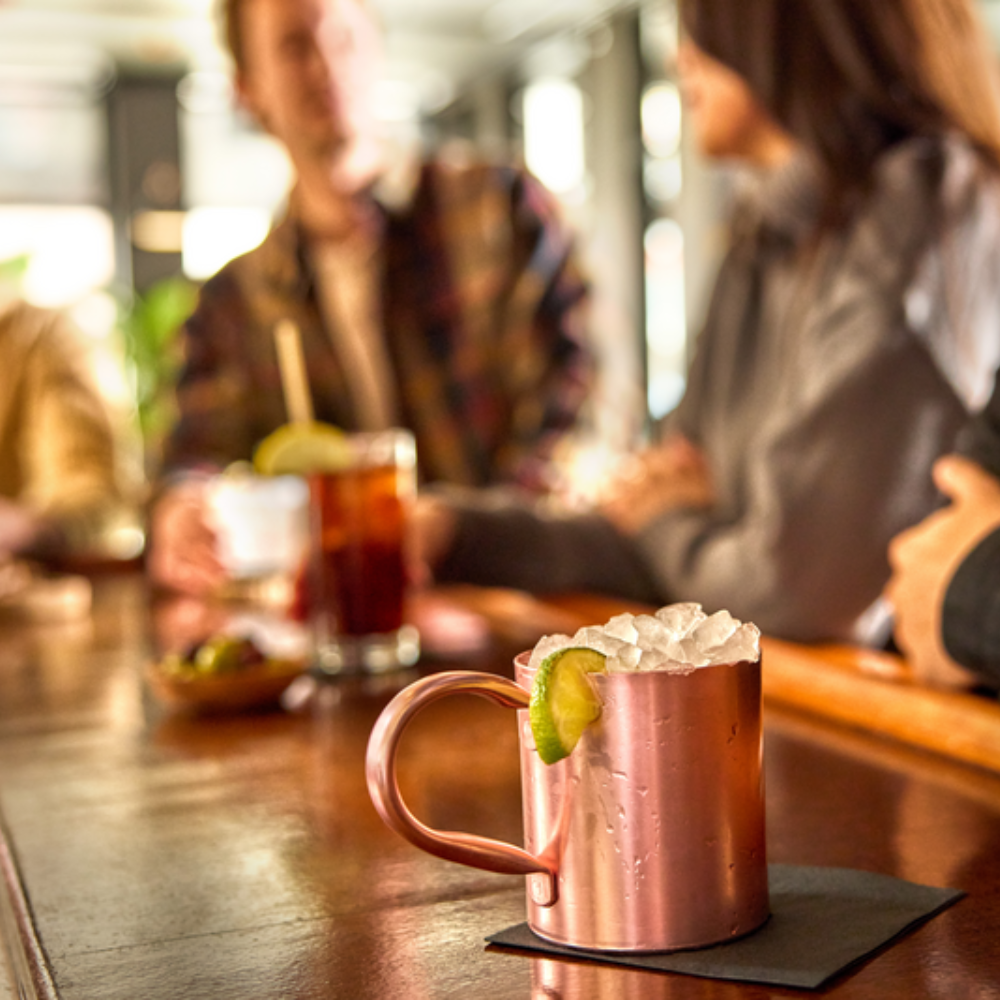 cold drinks filled with ice in a bar with people in the background