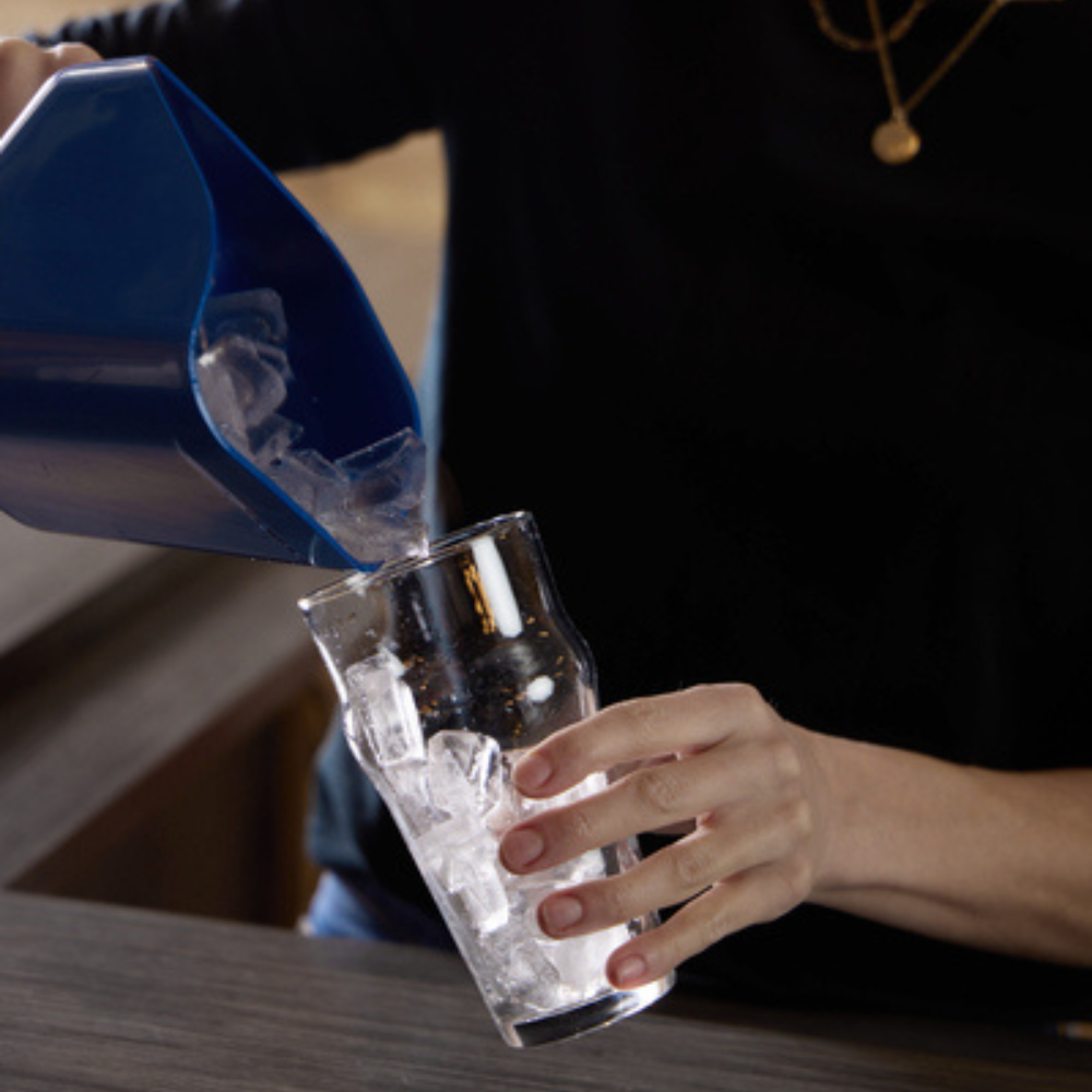 Server pouring ice into a glass cup from a blue ice scooper
