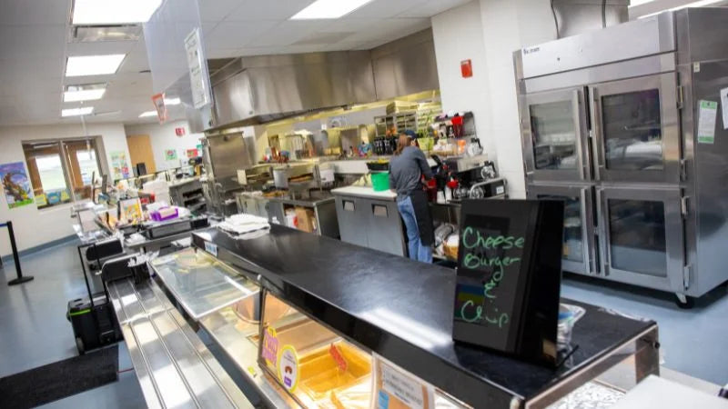 Commercial kitchen with stainless steel appliances and a person working.