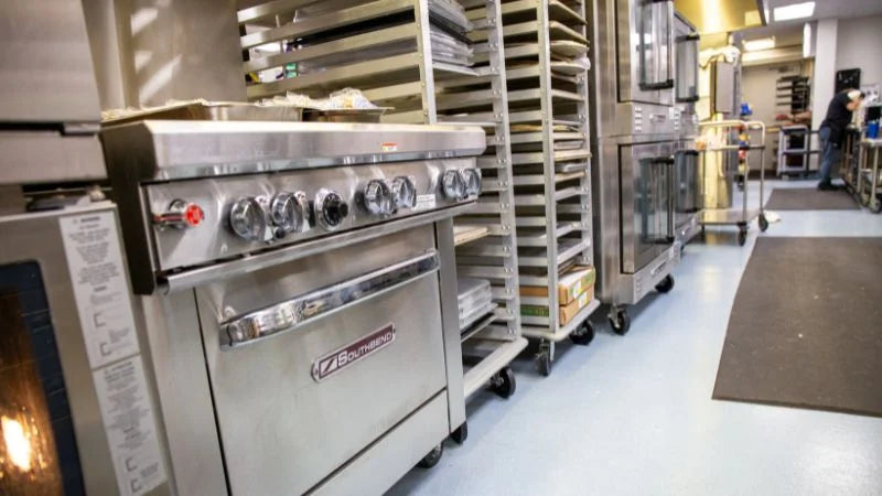 Commercial kitchen with stainless steel ovens and baking racks.