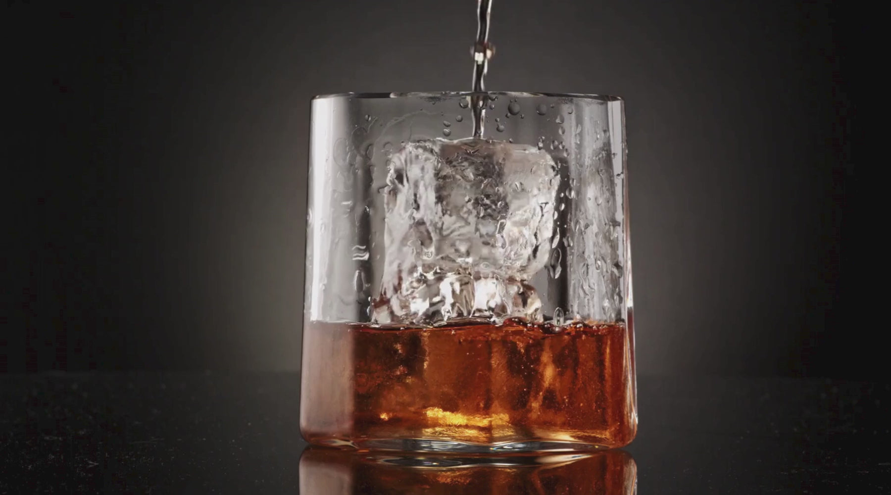Load video: Pouring a drink over a clear Scotsman gourmet ice cube in a rocks glass.