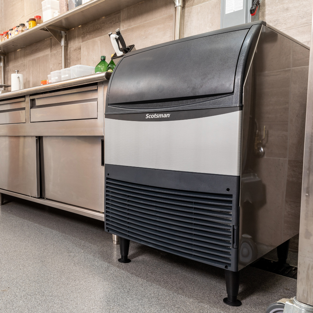 Scotsman undercounter ice machine next to a prep counter in a commercial kitchen.