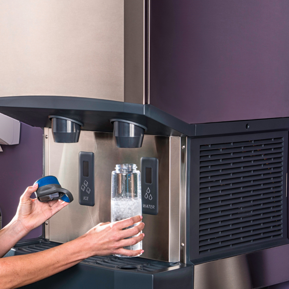 Woman using a Scotsman ice dispenser with touchless dispensing to fill a water bottle