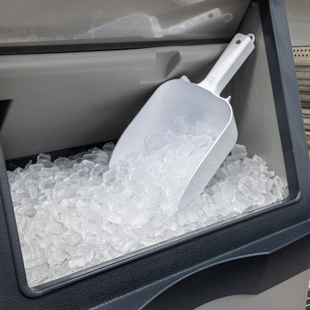 Close-up of an open ice bin with an ice scoop inside.